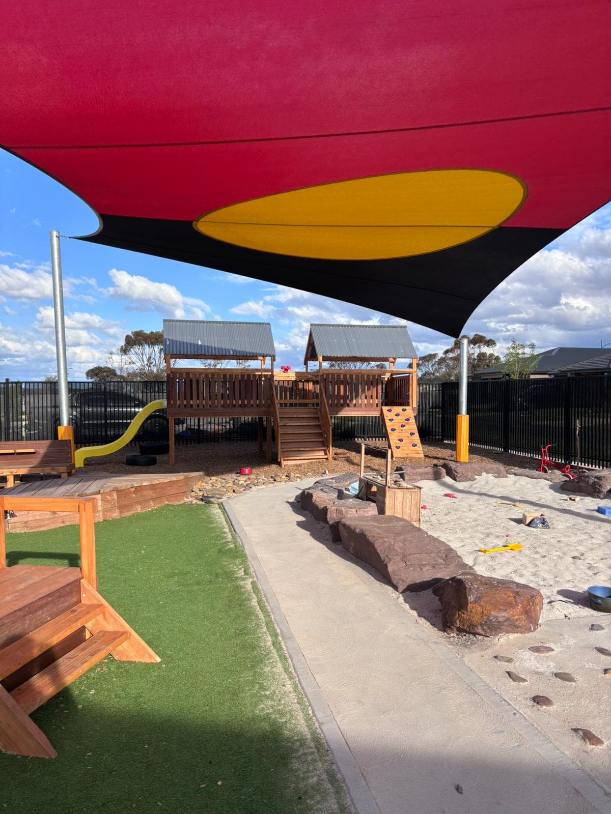 Large timber playground structure with climbing wall and steps